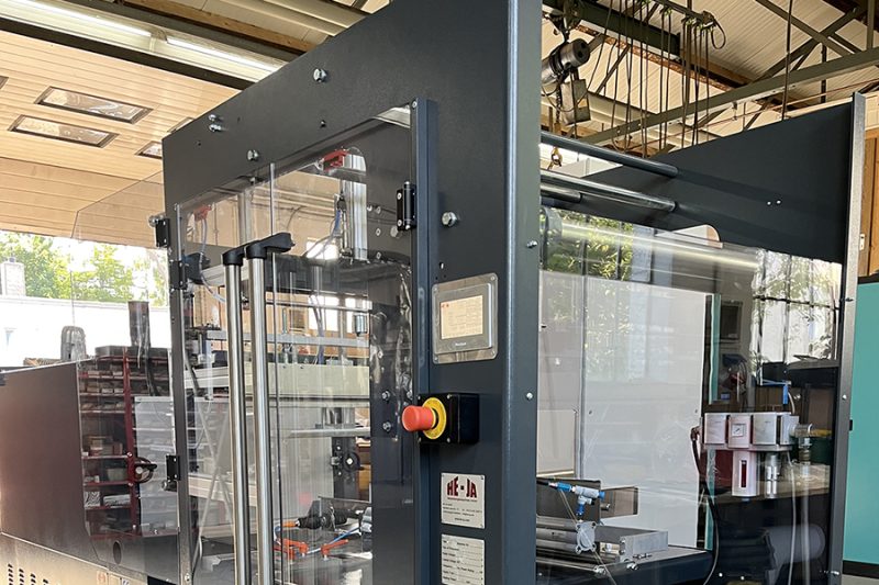 Foto einer von einer Polycarbonat-Hülle umgebenen Maschine in einer Werkshalle